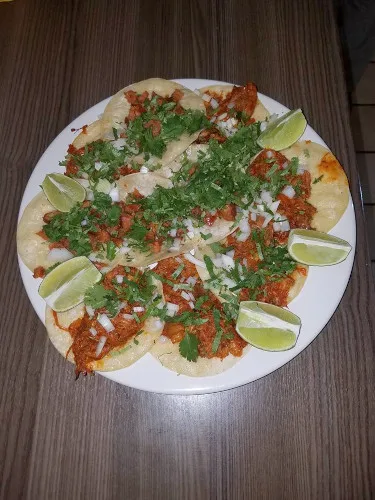 Tacos topped with cilantro and onion, with lime wedges
