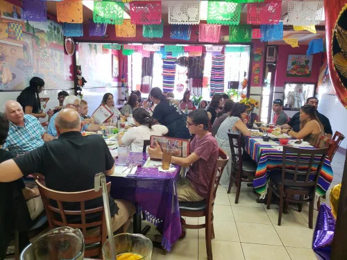 Guests at tables in the dining room under strings of papel picado