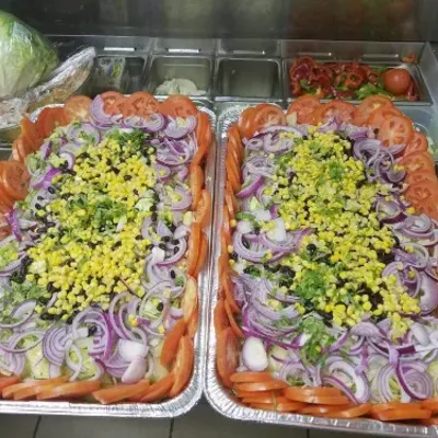 Two trays of salad with purple onion, corn and tomato