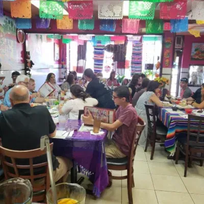 Guests at tables in the dining room under strings of papel picado